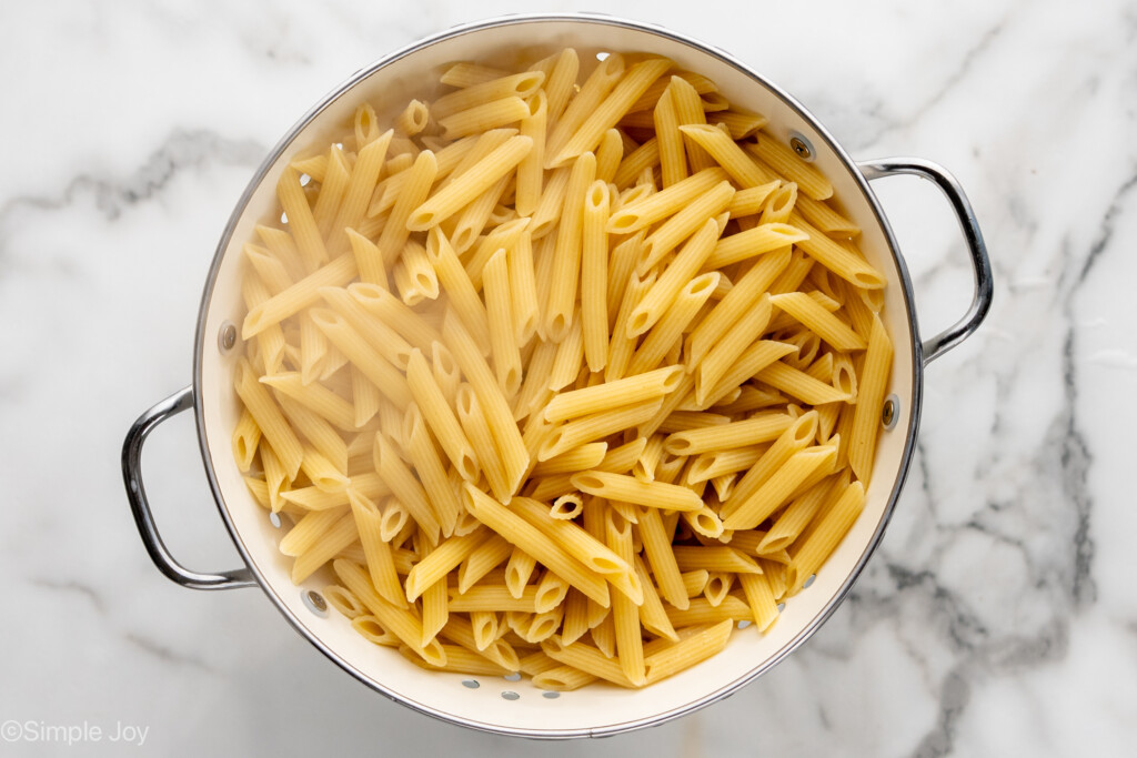 overhead of penne pasta in a strainer