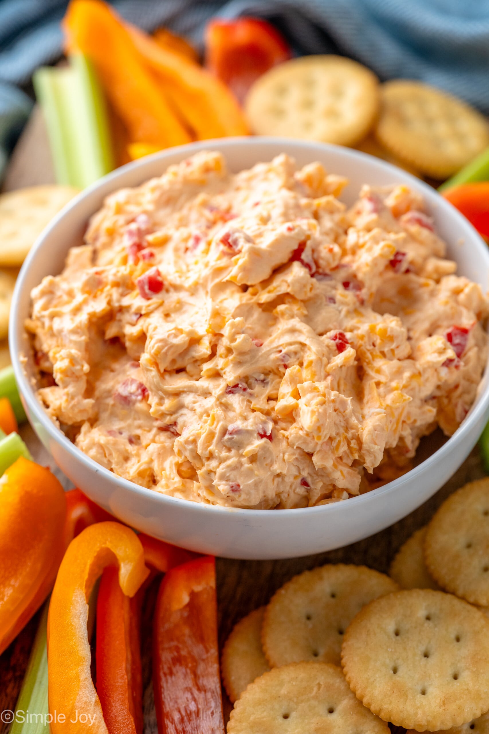 Bowl of Pimento Cheese recipe surrounded by crackers and sliced vegetables
