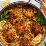 Pinterest graphic for Chicken and Rice. Image shows overhead of pan of Chicken and Rice garnished with lemon slices and parsley. Lemon slices, parsley, and bread sitting beside. Says "the best chicken & rice simplejoy.com"