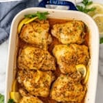 Pinterest graphic for Greek Chicken. Says "the best Greek Chicken simplejoy.com" Image shows overhead of baking dish of Greek Chicken with fresh parsley and lemon slices