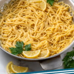 Pinterest graphic for lemon pasta. Image shows skillet of lemon pasta garnished with parsley and lemon slices, two glasses of white wine sitting in background. Says "lemon pasta simplejoy.com"