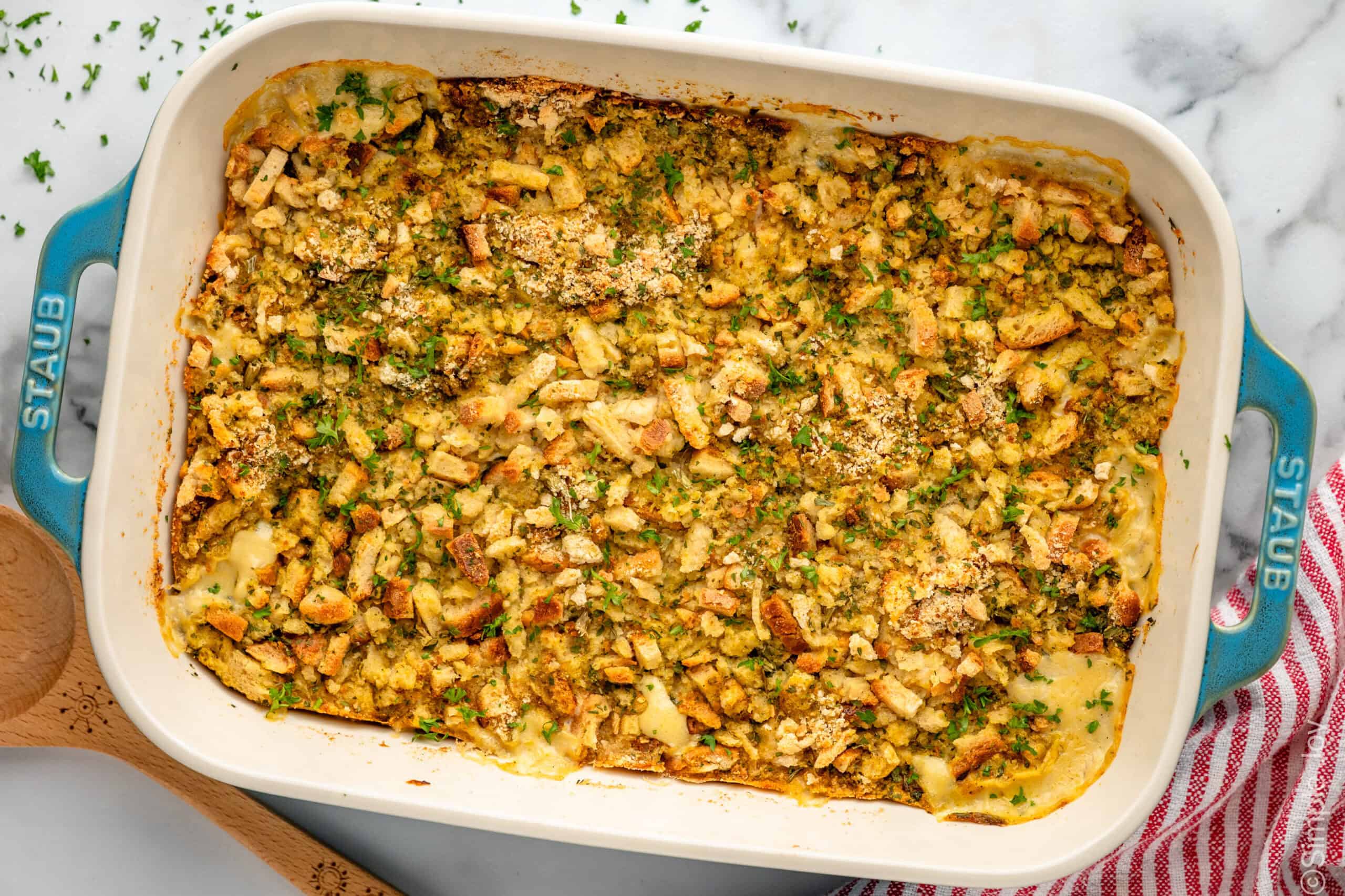 Overhead view of a baking dish of Chicken and Stuffing Casserole with wooden spoon beside