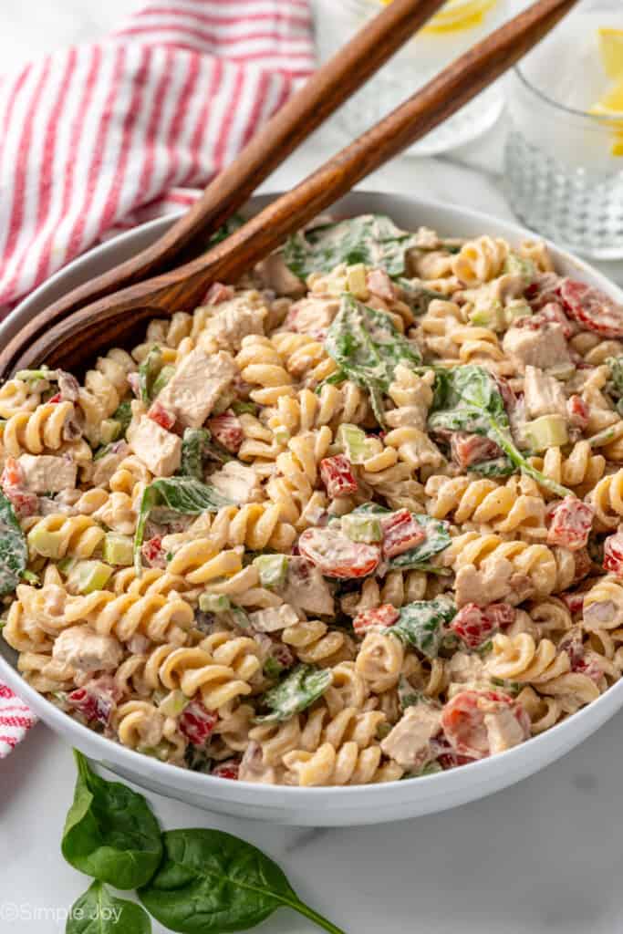 white bowl of chicken pasta salad recipe with wooden spoons for serving
