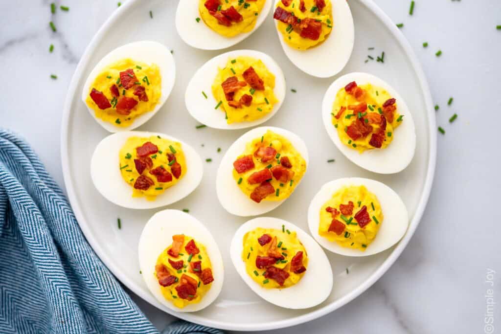 overhead of a plate of deviled eggs topped with bacon