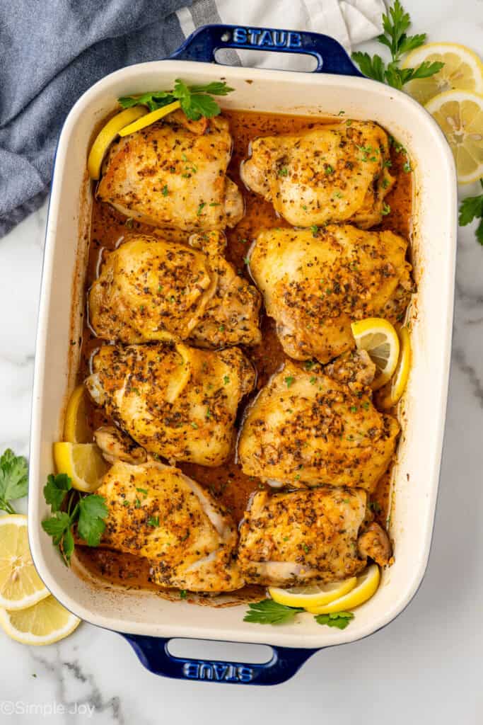 Overhead of baking dish of Greek Chicken recipe garnished with lemon slices and parsley