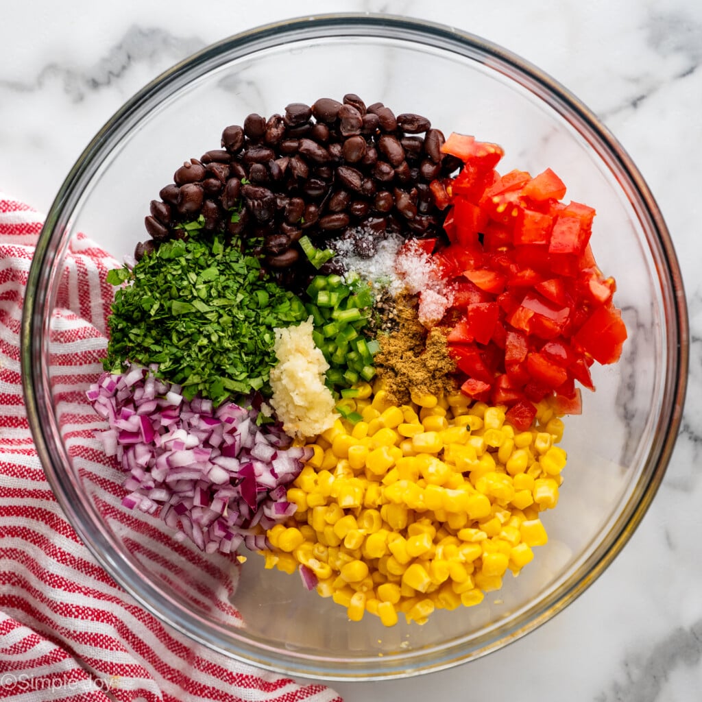 Overhead of glass bowl of Black Bean and Corn Salsa ingredients