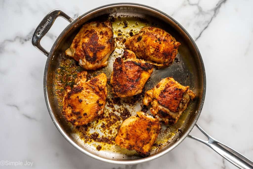 Overhead of seared chicken thighs in skillet to make chicken and rice.