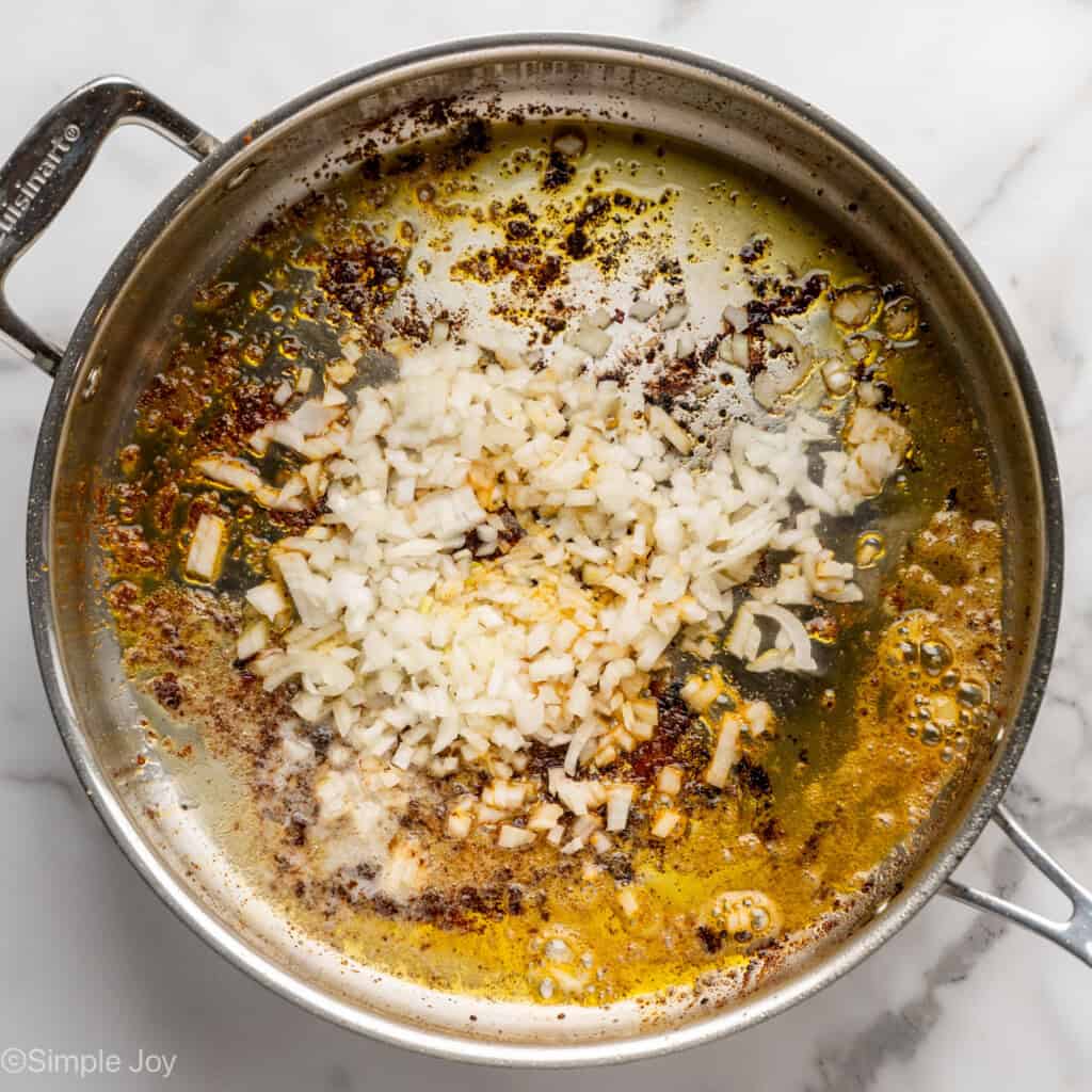 Overhead of skillet of onion cooking to make chicken and rice recipe