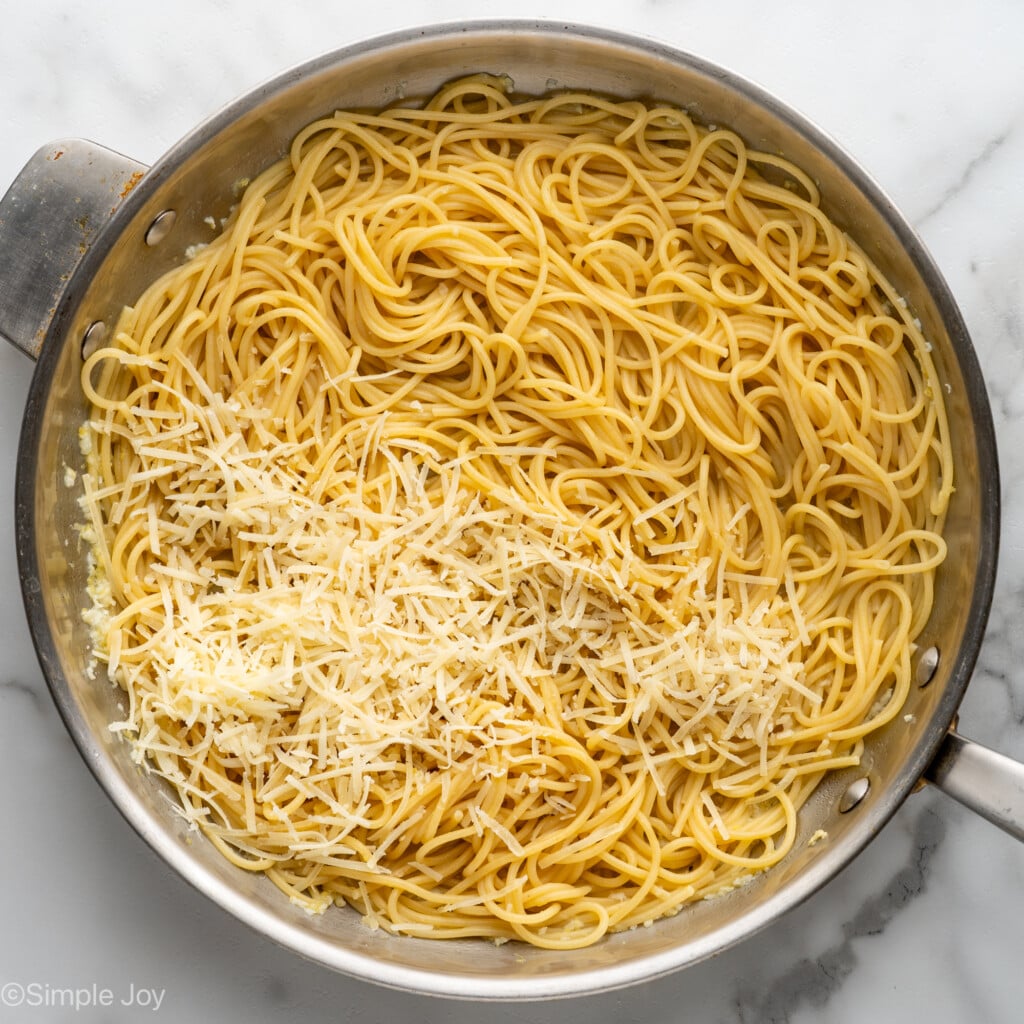 Overhead of pasta and shredded cheese in skillet to make lemon pasta recipe