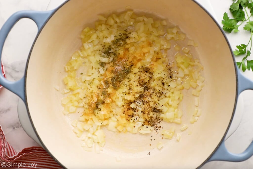 overhead of Dutch oven of onion and seasonings to make scalloped potatoes and ham recipe