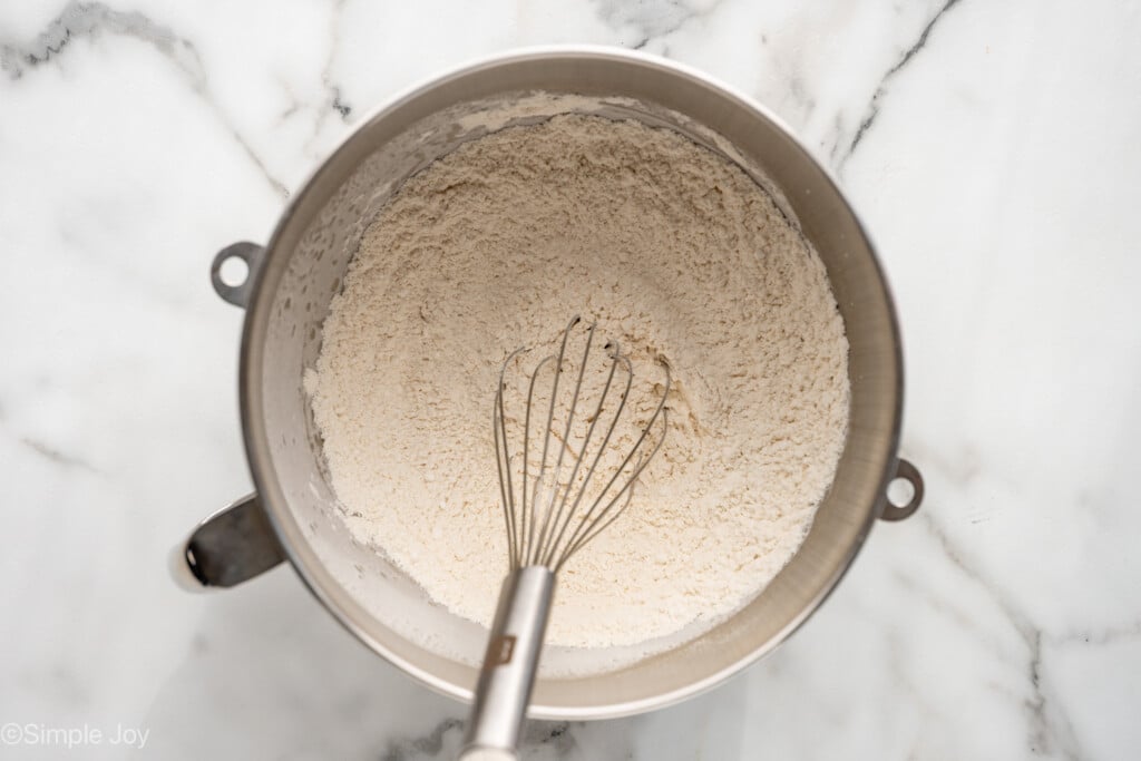 overhead of metal mixing bowl of shortbread cookie recipe ingredients with a whisk