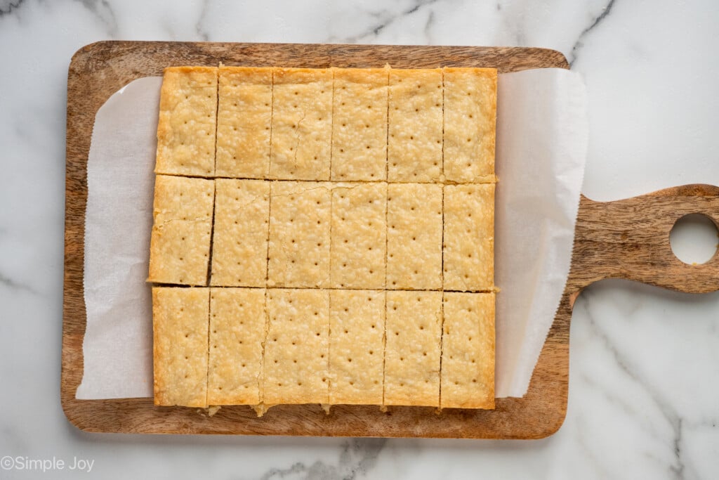 overhead of homemade shortbread cookie recipe cut into rectangles on a parchment paper lined wooden cutting board