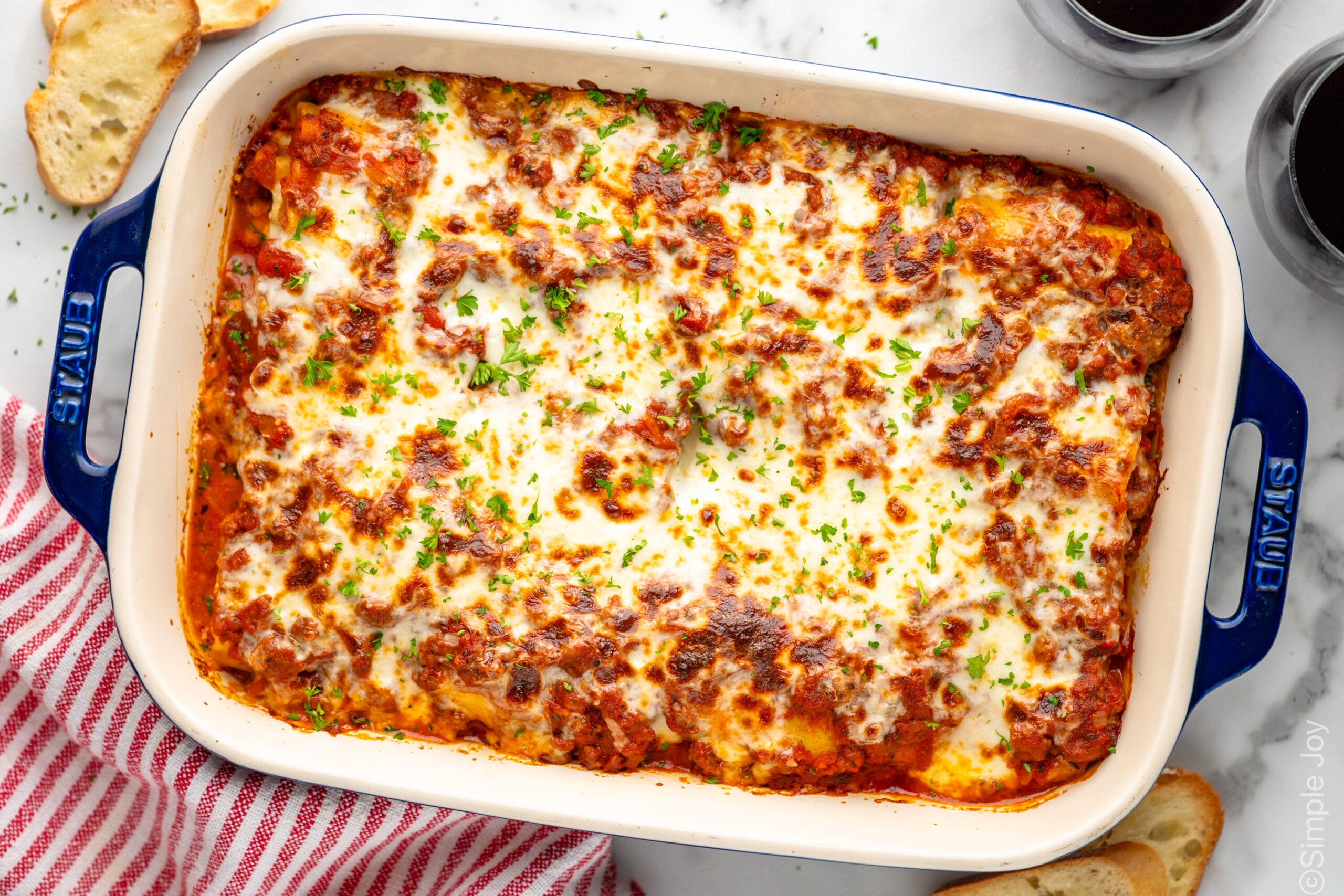 Overhead view of baking dish of Lasagna Roll Ups garnished with fresh parsley. Garlic bread beside