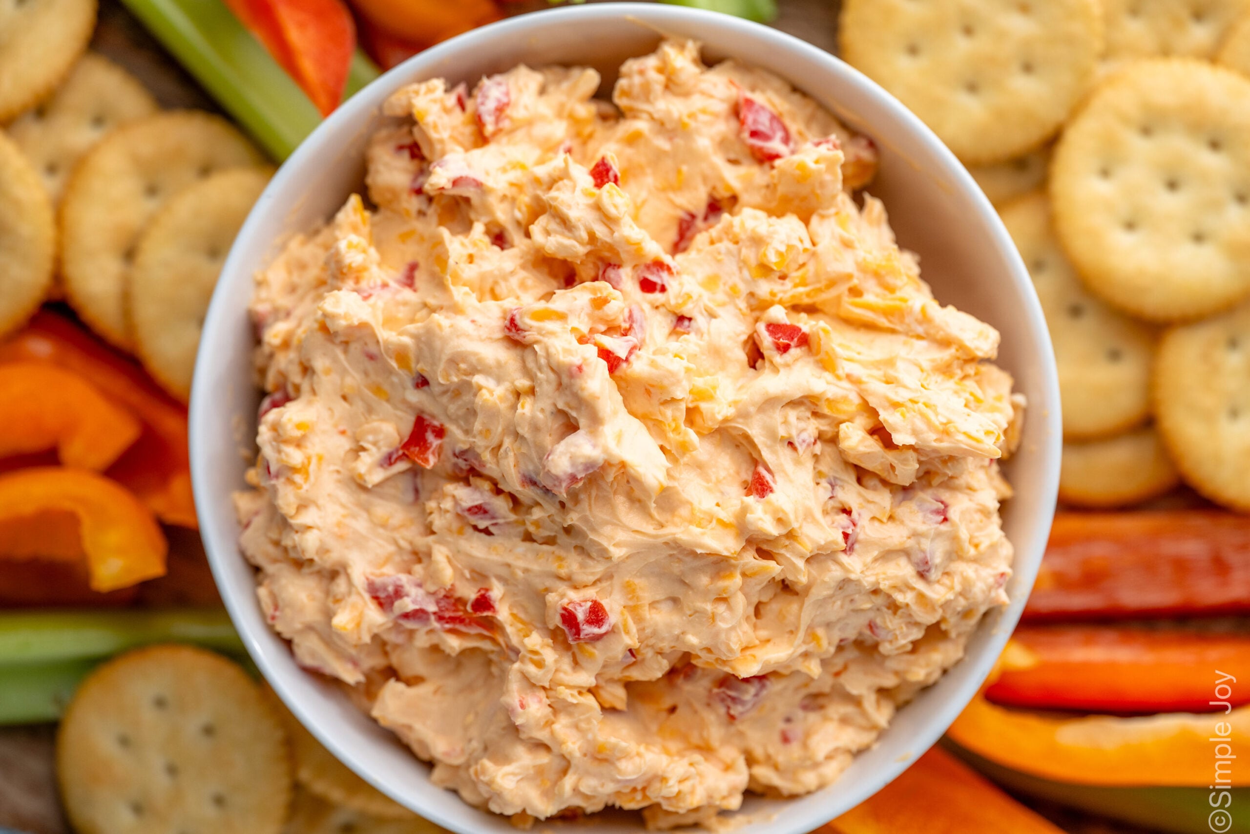 Overhead view of a bowl of Pimento Cheese surrounded by crackers and cut-up vegetables