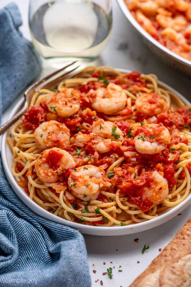 Plate of pasta topped with Shrimp Fra Diavolo and fresh parsley with a fork