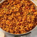 Pinterest graphic for American Chop Suey. Image shows skillet of American Chop Suey recipe. Says "one pot American Chop Suey simplejoy.com"