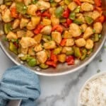 Pinterest graphic for Sweet and Sour Chicken. Image shows overhead of skillet of Sweet and Sour Chicken with bowl of white rice beside. Says "super easy Sweet and Sour Chicken simplejoy.com"