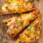 sliced BBQ Chicken Flatbread Pizza on a wooden cutting board garnished with fresh cilantro