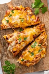 sliced BBQ Chicken Flatbread Pizza on a wooden cutting board garnished with fresh cilantro