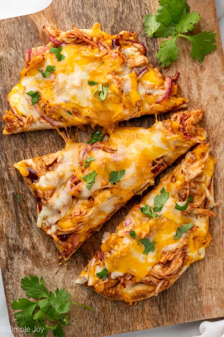 sliced BBQ Chicken Flatbread Pizza on a wooden cutting board garnished with fresh cilantro
