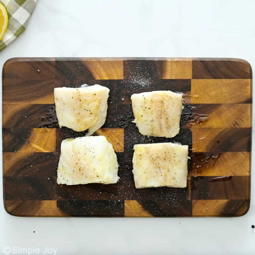 Overhead of cod filets on a wooden cutting board to make Air Fryer Cod recipe
