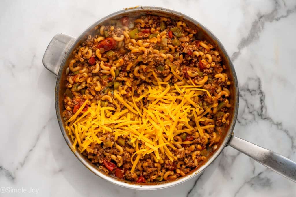 Overhead of skillet of American Chop Suey topped with shredded cheese