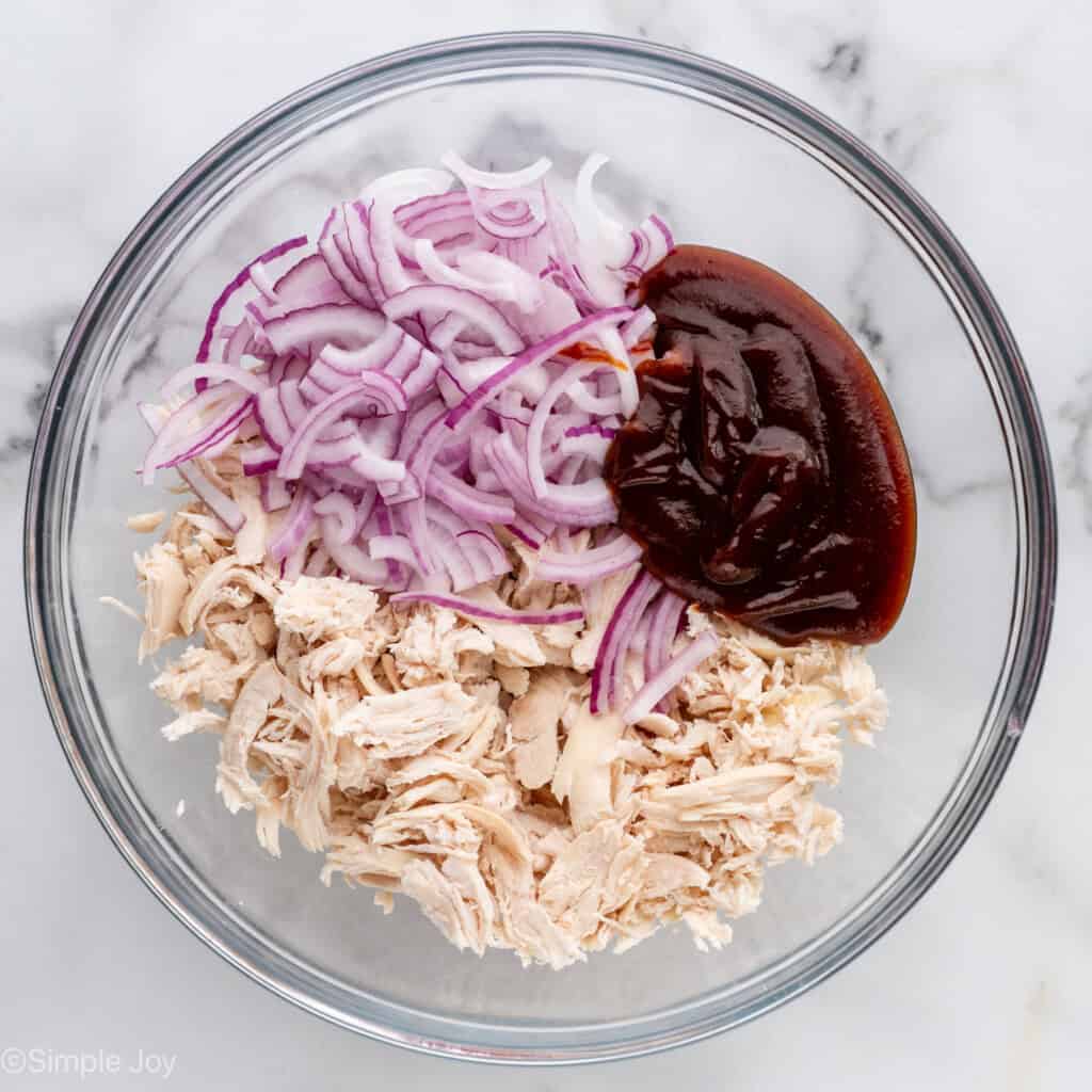 Overhead of glass bowl of BBQ Chicken Flatbread Pizza ingredients with spoon