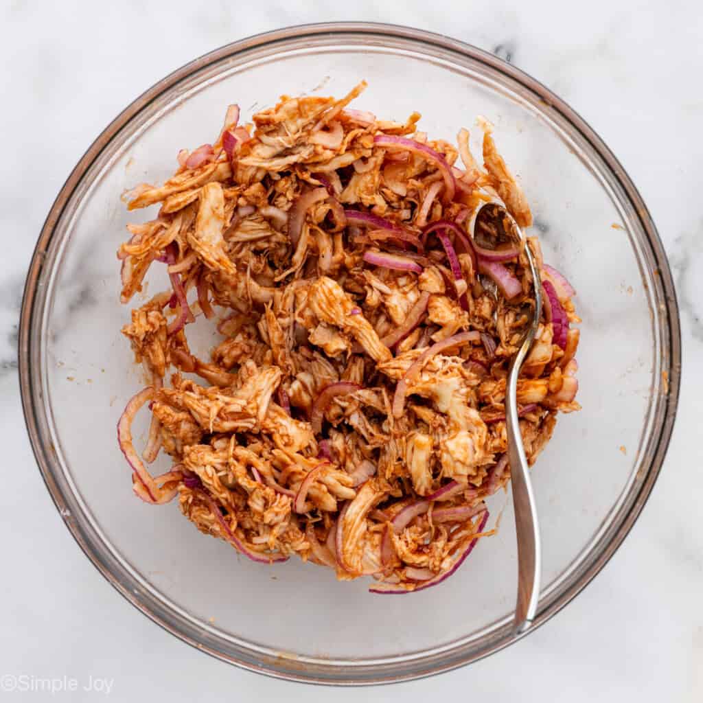 Overhead of glass bowl of BBQ Chicken Flatbread Pizza ingredients with spoon