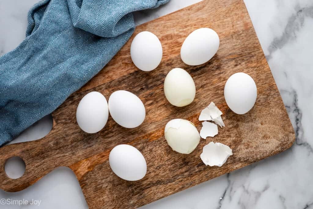 Overhead of hard boiled eggs on a wooden cutting board to make cottage cheese egg salad recipe