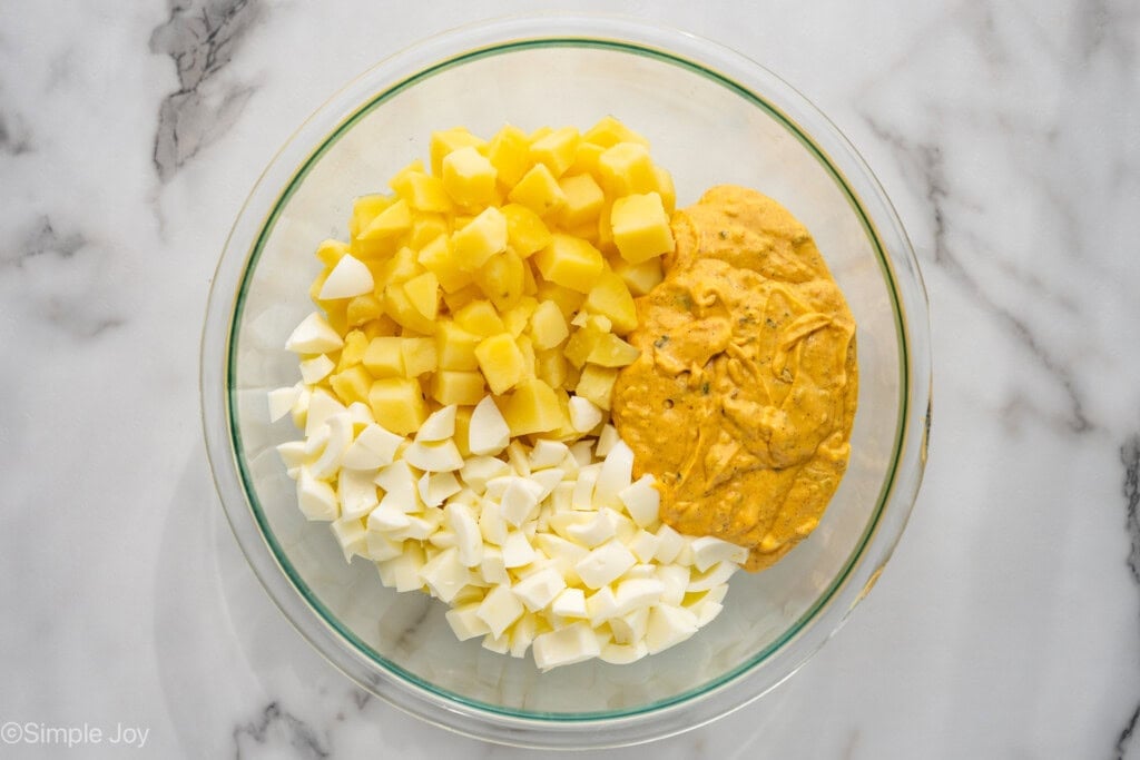 Overhead of glass bowl of Deviled Egg Potato Salad ingredients