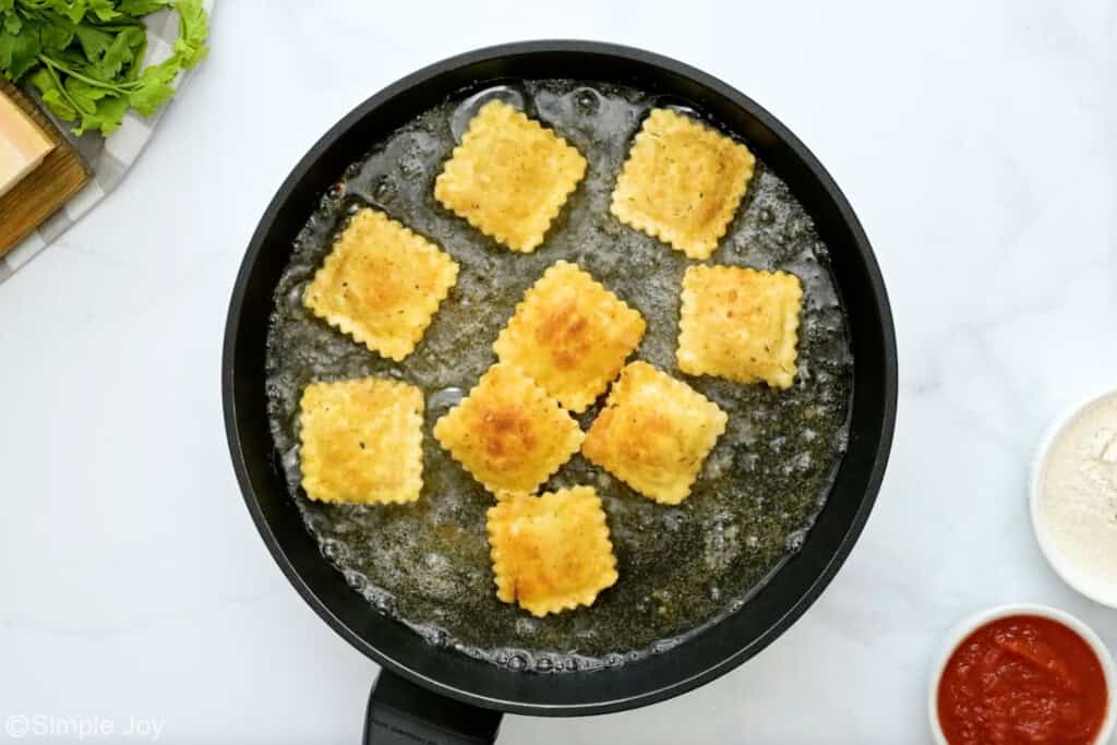 overhead of skillet of friend ravioli cooking in oil