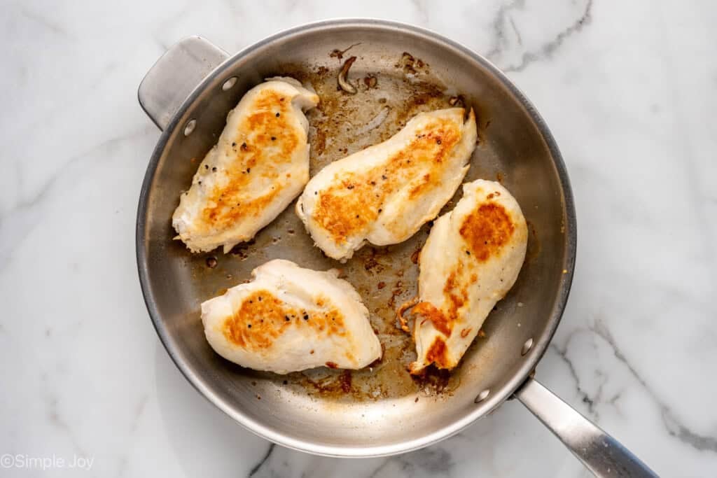 Overhead of skillet of chicken breasts to make Mediterranean Chicken and Orzo recipe