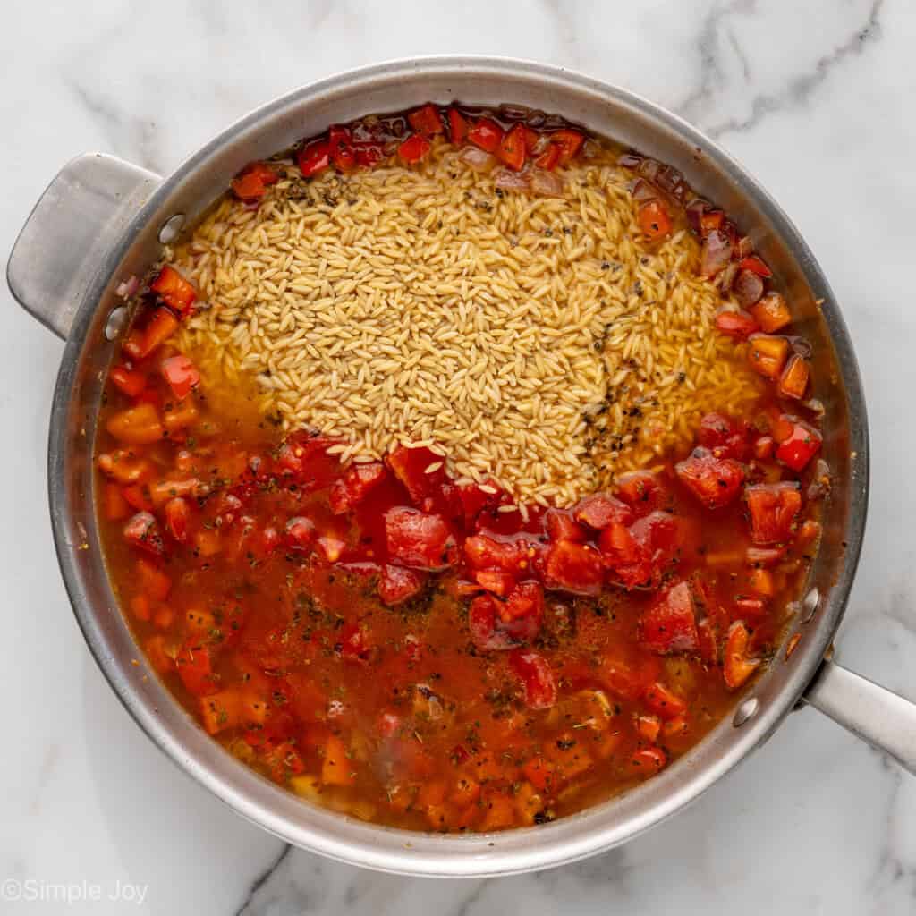 Overhead of skillet of Mediterranean Chicken and Orzo ingredients