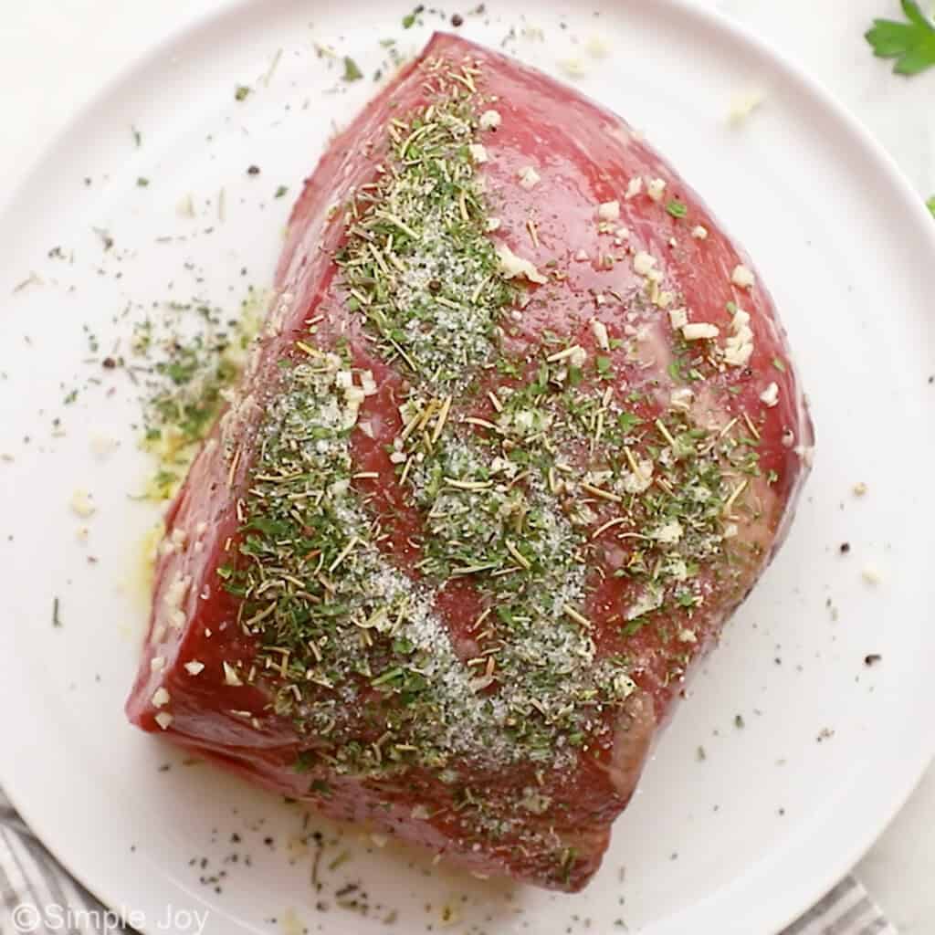 Overhead of sirloin tip roast with seasonings on a plate
