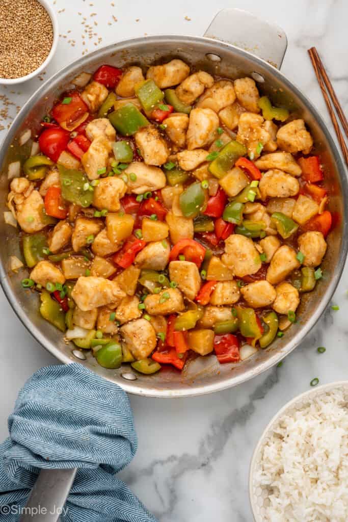 Overhead of skillet of Sweet and Sour Chicken recipe with bowl of white rice sitting beside
