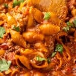 Pinterest graphic for One Pan Cheesy Taco Pasta. Image shows close up of wooden spoon in One Pan Cheesy Taco Pasta, says "One Pan Cheesy Taco Pasta simplejoy.com"