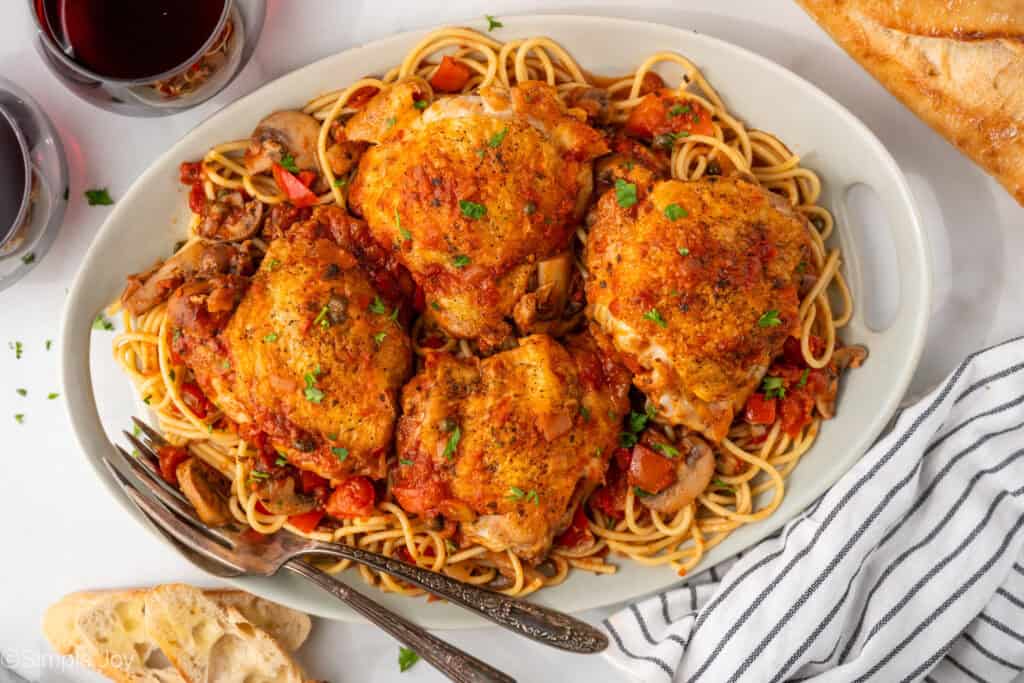 Overhead of platter of Chicken Cacciatore with forks for serving
