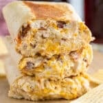 three crack chicken wraps stacked on top of each other with potato chips sitting beside