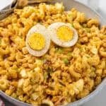 Bowl of Deviled Egg Pasta Salad garnished with a hard boiled egg and paprika with two forks