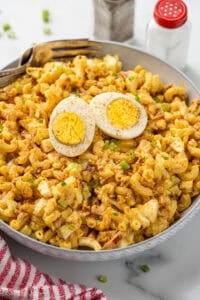 Bowl of Deviled Egg Pasta Salad garnished with a hard boiled egg and paprika with two forks