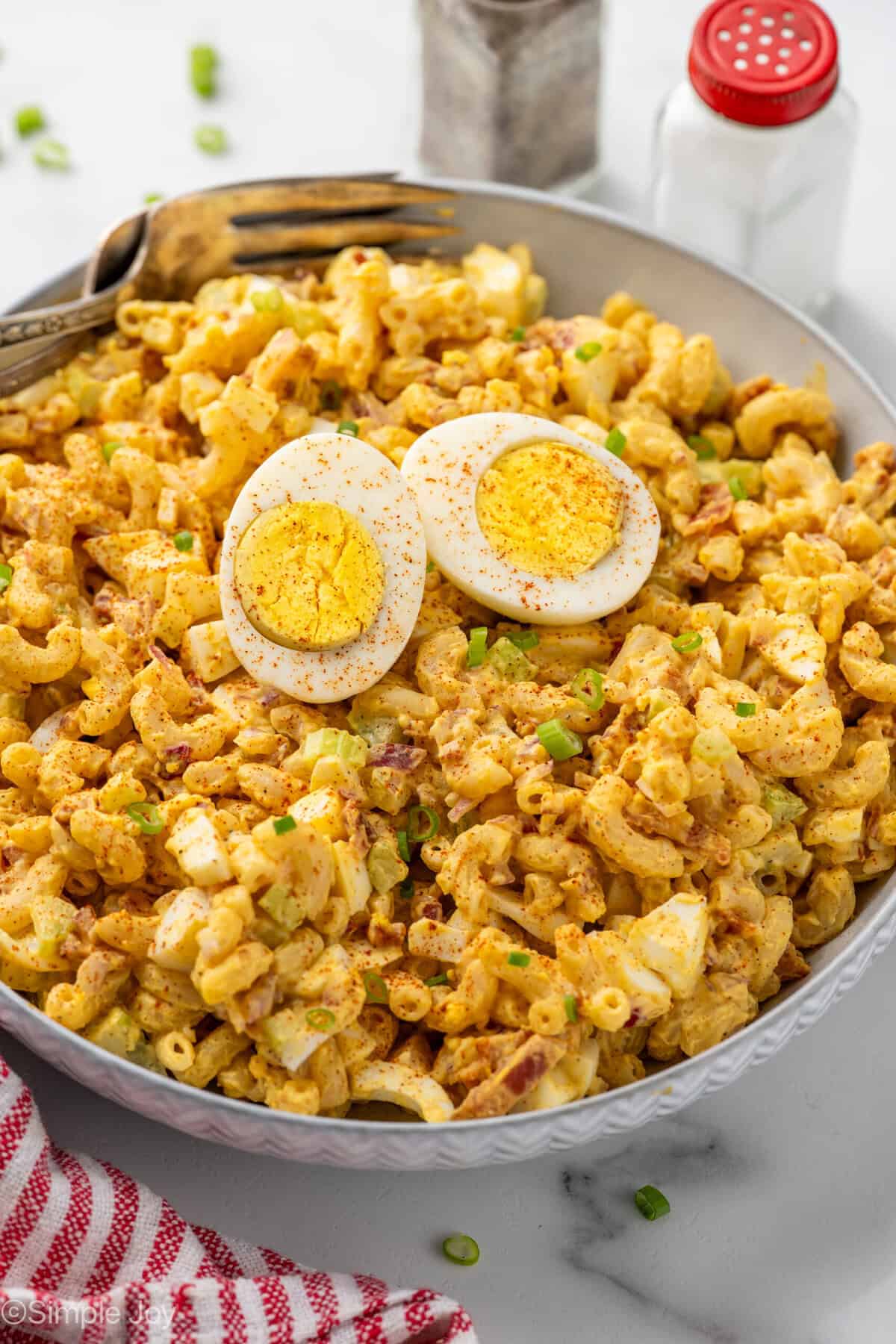 Bowl of Deviled Egg Pasta Salad garnished with a hard boiled egg and paprika with two forks