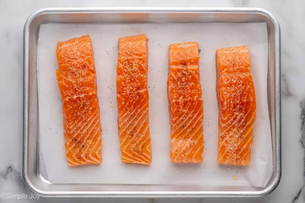 Overhead of salmon fillets on a parchment lined baking sheet to make Broiled Salmon with Lemon Dill Sauce