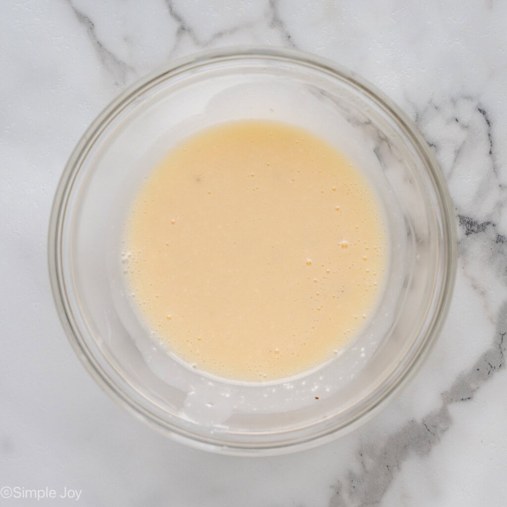 Overhead of glass bowl of apple slaw dressing ingredients
