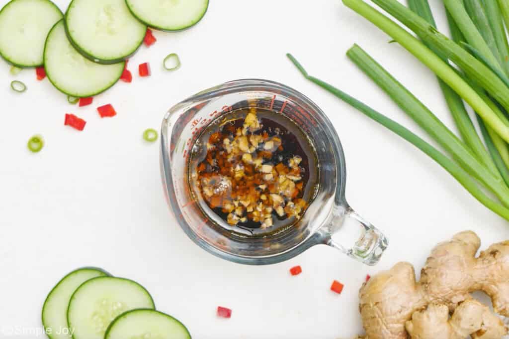 Overhead of glass measuring cup of asian cucumber salad dressing ingredients