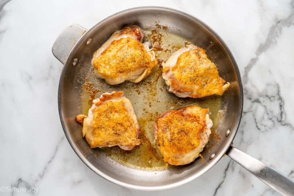 Overhead of chicken thighs cooking in a skillet to make Chicken Cacciatore recipe