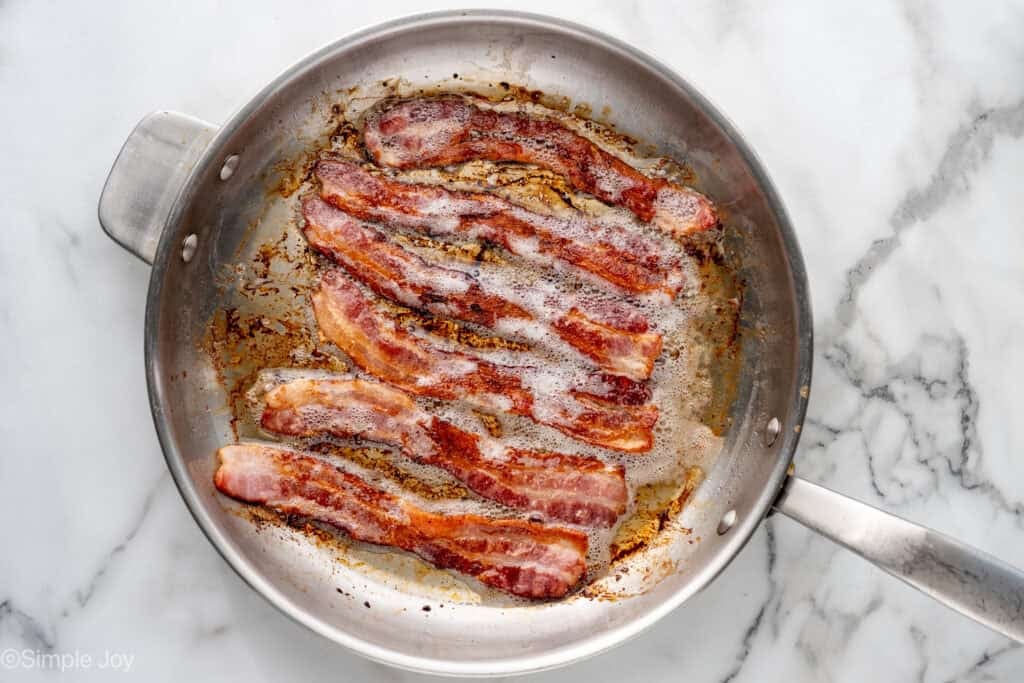Overhead of bacon cooking in a skillet to make Deviled Egg Pasta Salad
