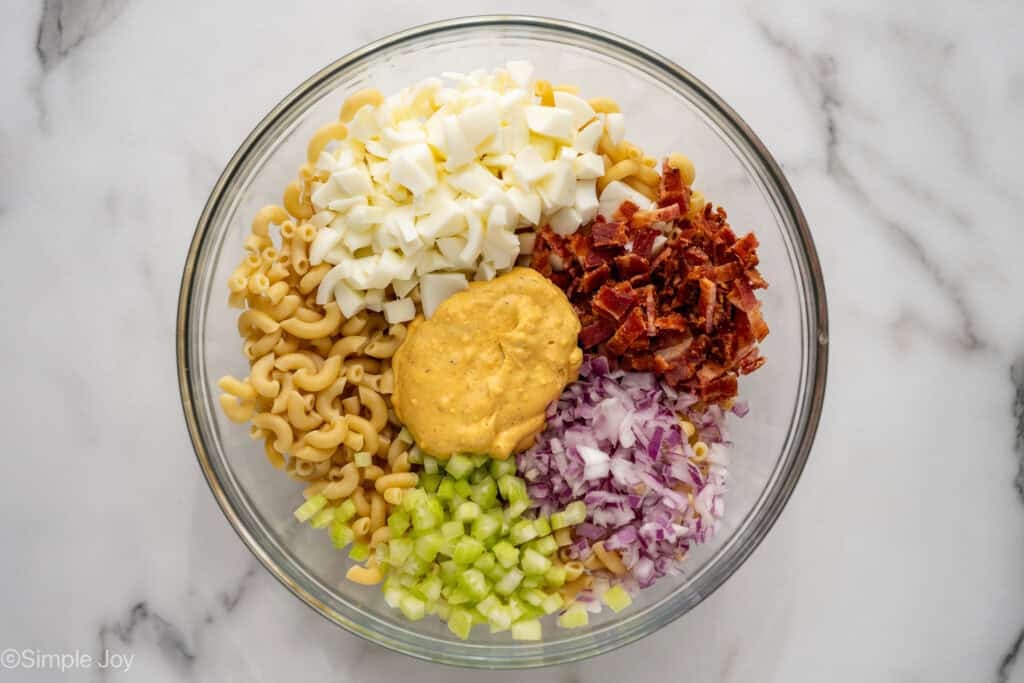 Overhead of glass bowl of Deviled Egg Pasta Salad ingredients