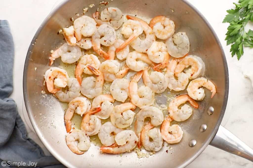 Overhead of skillet of shrimp cooking in butter to make garlic butter shrimp