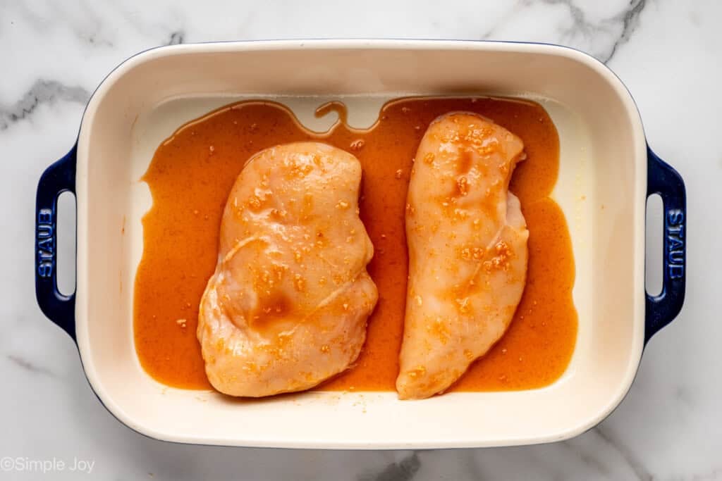 Overhead of baking dish of Honey Sriracha Chicken breasts and marinade to make Honey Sriracha Chicken Bowls