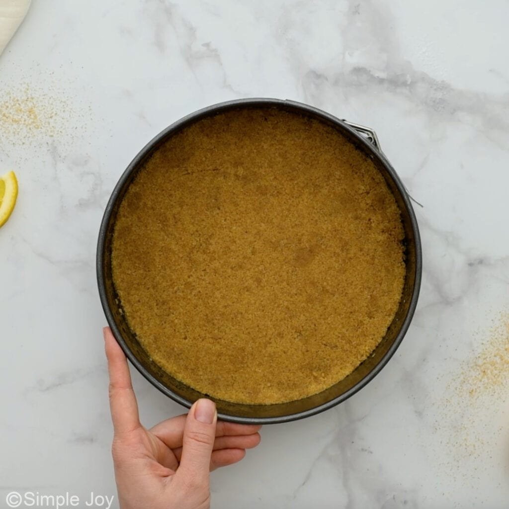 Overhead of graham crust in a springform pan to make lemon cheesecake
